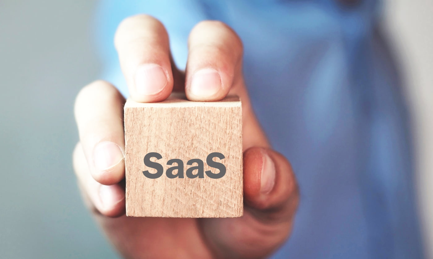 man holding wooden block with SaaS written on it